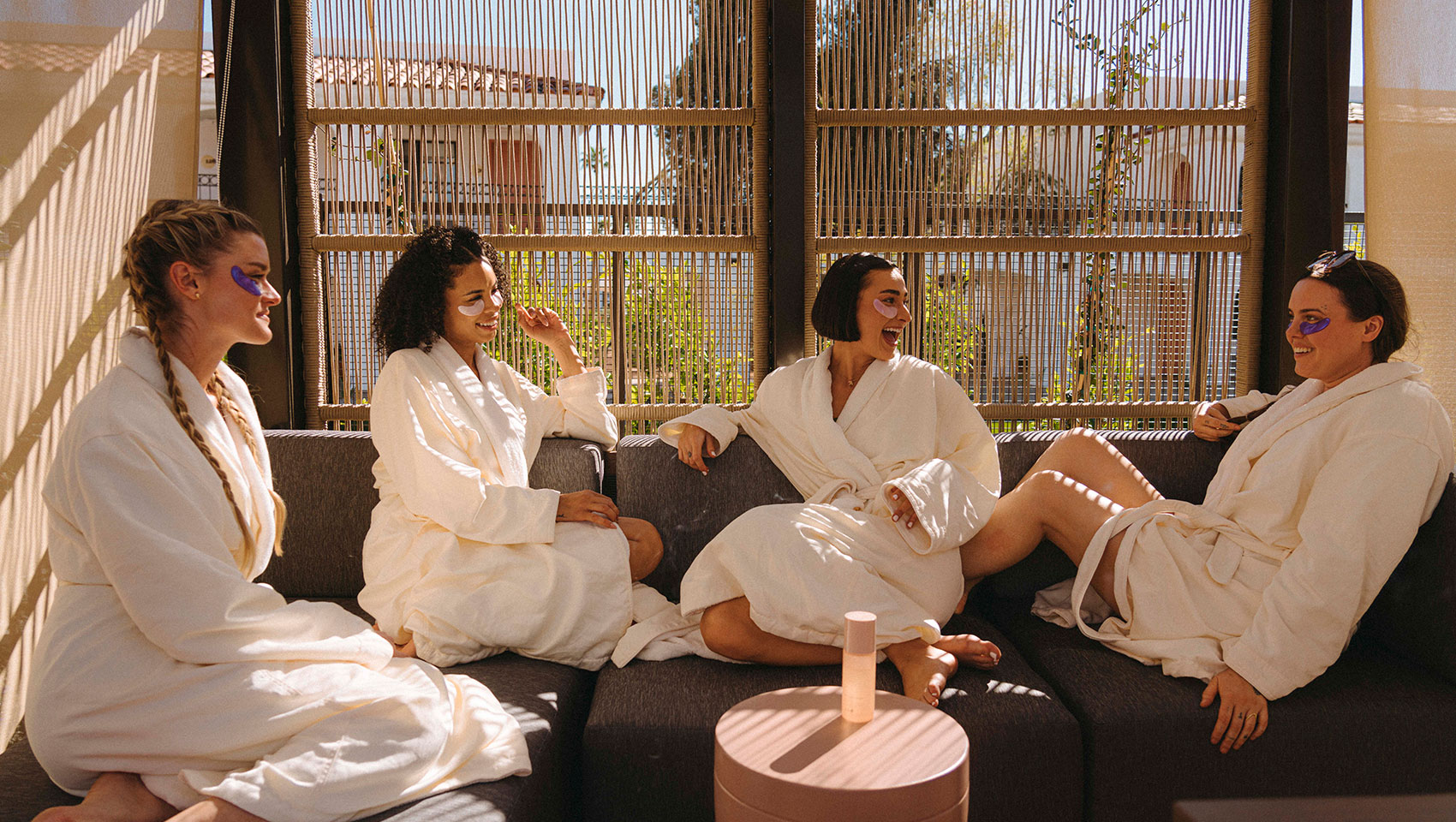 women in spa robes sitting outside with eye masks
