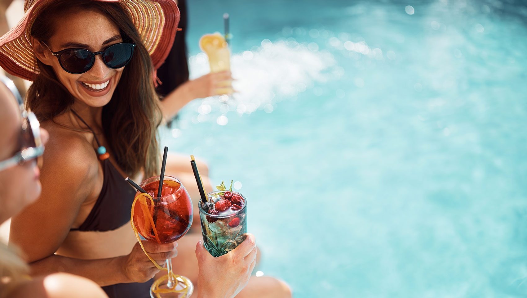 group of women drinking cocktails by the pool
