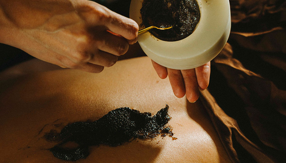 Wellness practitioner putting a substance on someone's back