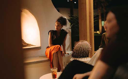 Woman sitting by Outdoor Fireplace at Kimpton Miralina