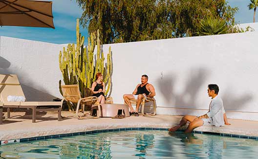 Adults sitting and chatting on pool deck at Kimpton Miralina Resort