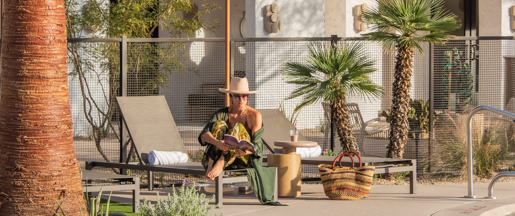 a woman sits on a lounge chair and reads a book by the pool at Kimpton Miralina